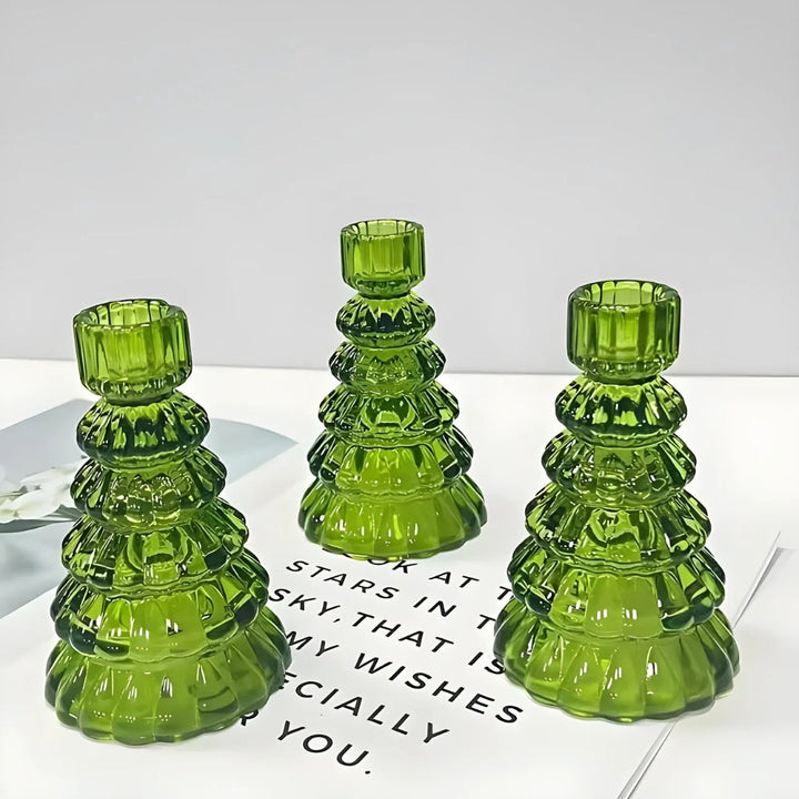 Three green glass Christmas tree-shaped candle holders on a white surface.