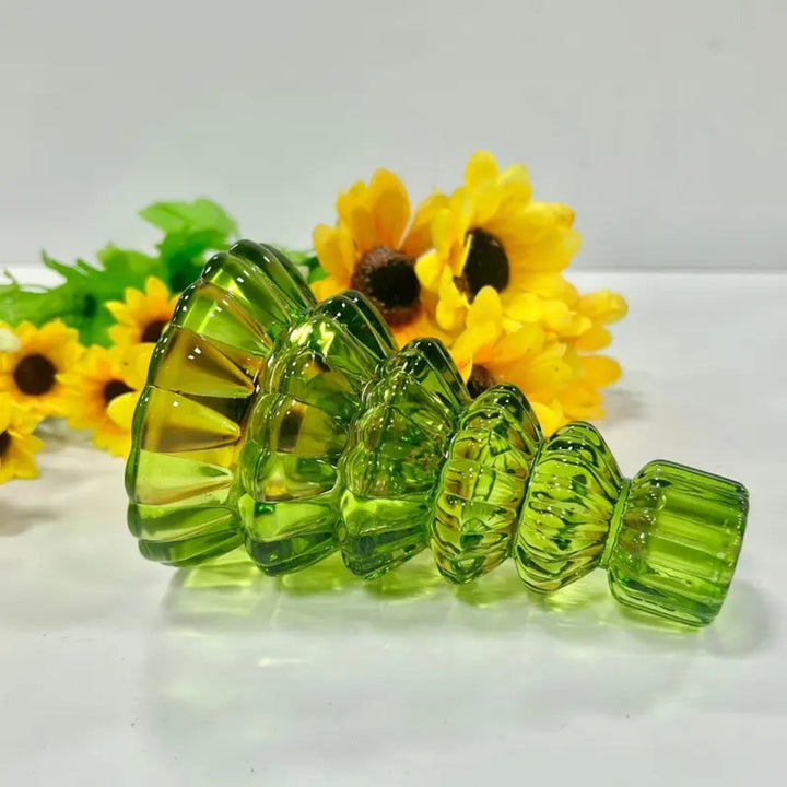 Green glass Christmas tree candle holder with ribbed details, set against yellow sunflowers.