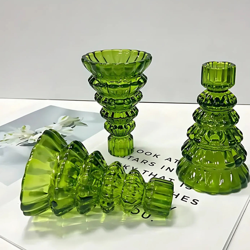 Three green glass Christmas tree candle holders arranged on a surface.