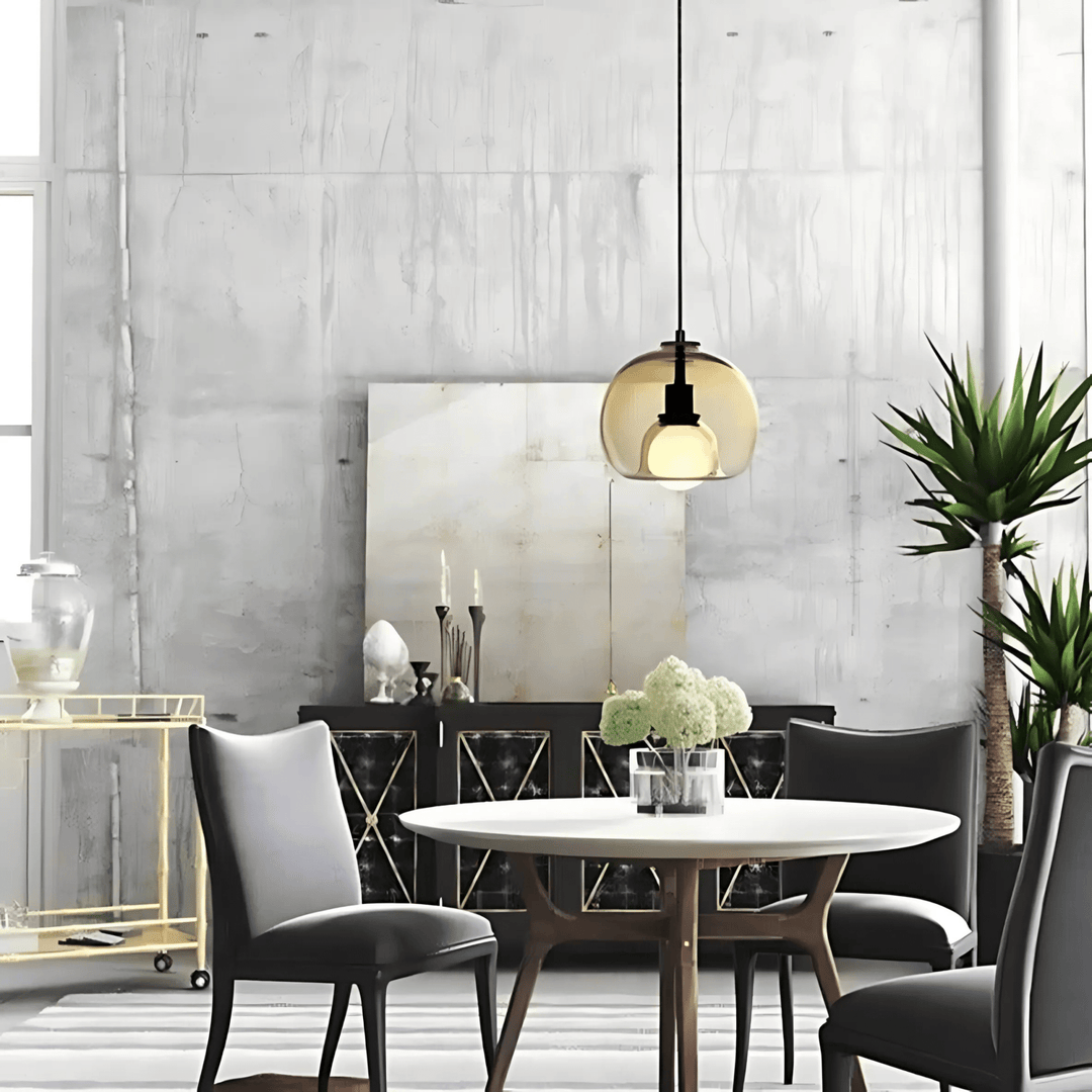 Amber handblown glass pendant light hangs above a round dining table with dark chairs.