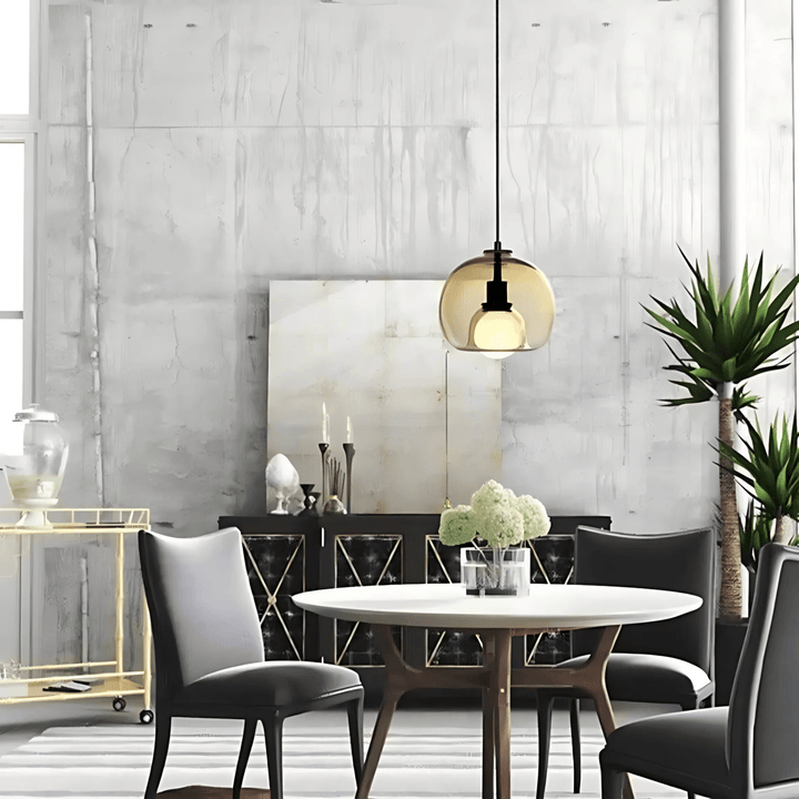 Amber handblown glass pendant light hangs above a round dining table with dark chairs.