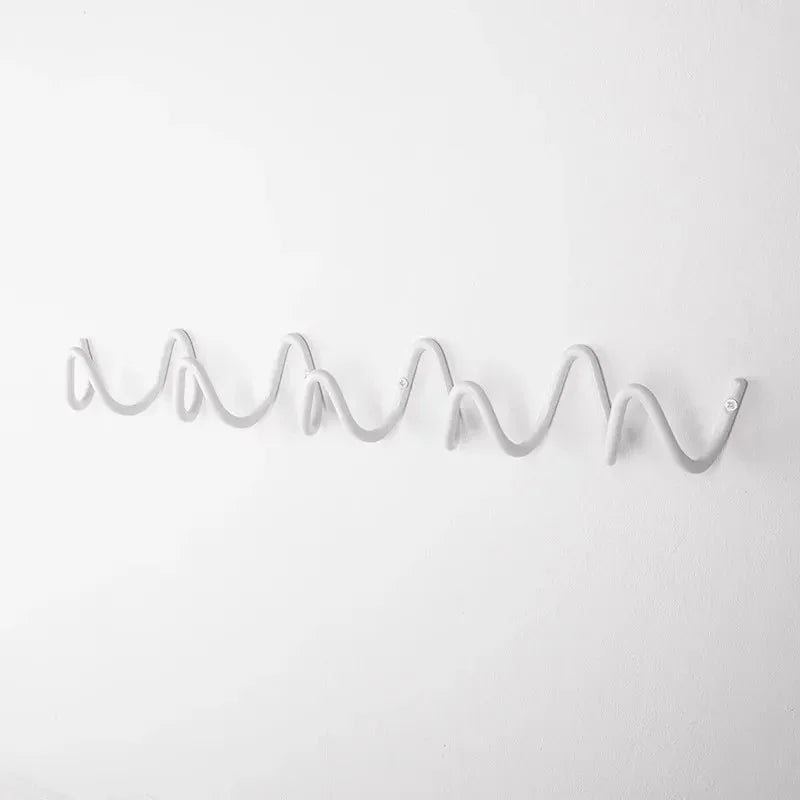 Wrought iron wall hook rack with a wavy, multi-hook design in a light gray color.