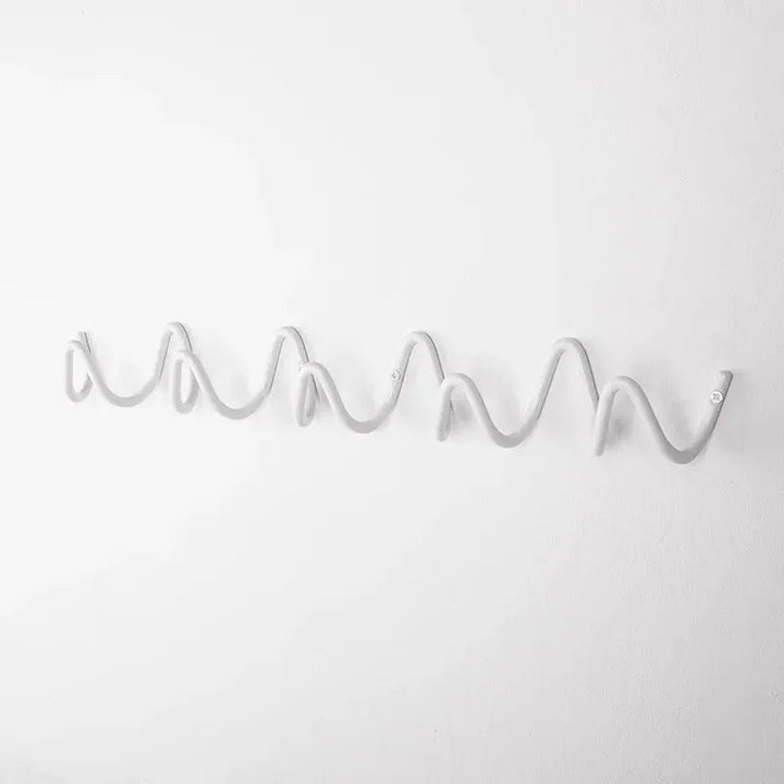 Wrought iron wall hook rack with a wavy, multi-hook design in a light gray color.