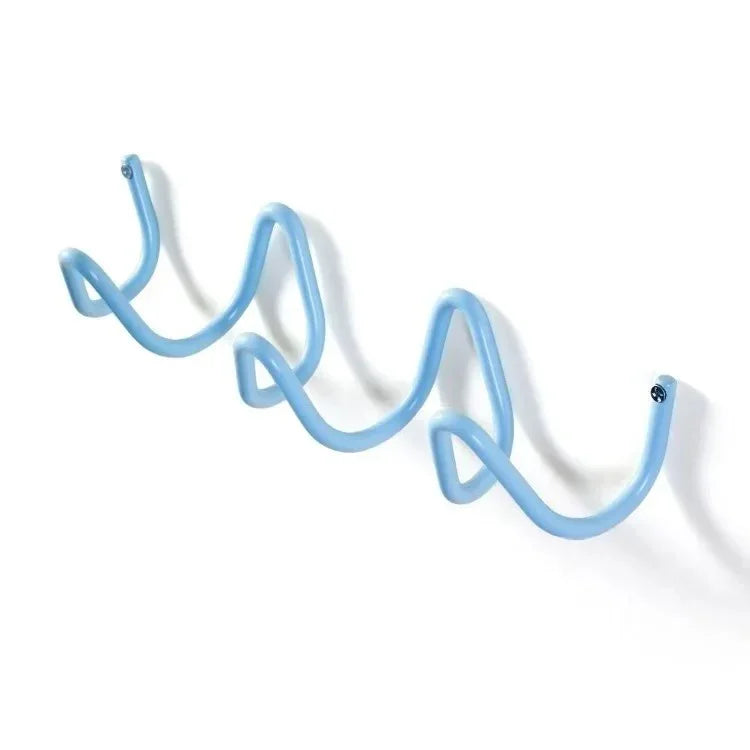 A light blue wrought iron wall hook rack with a wavy, serpentine design.