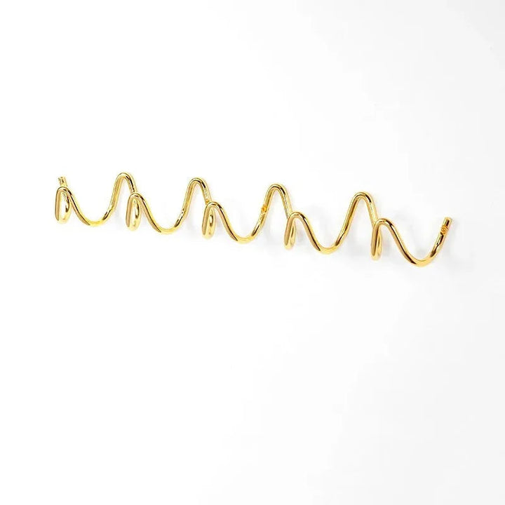 Gold wavy metal wall hook rack with multiple curves against a white background.