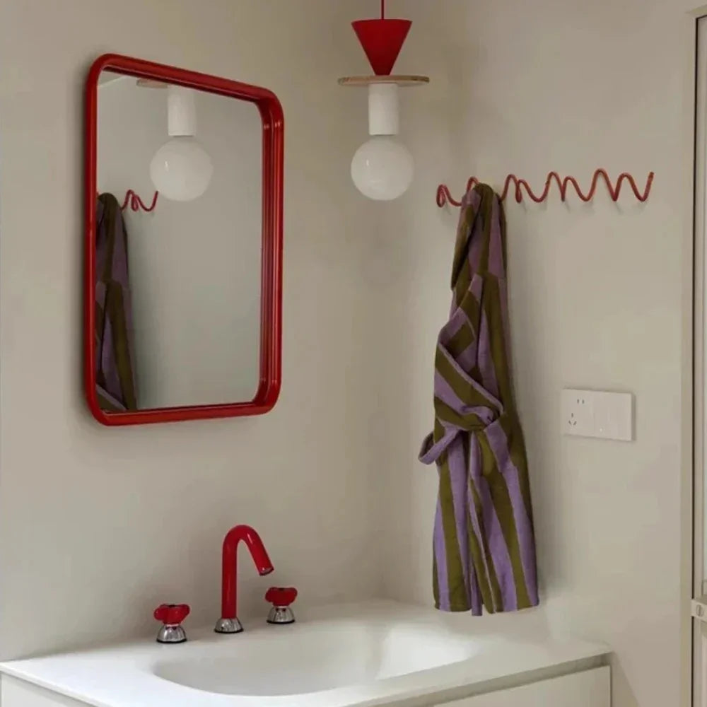 Red wavy wall hook rack with a striped robe hanging on it.
