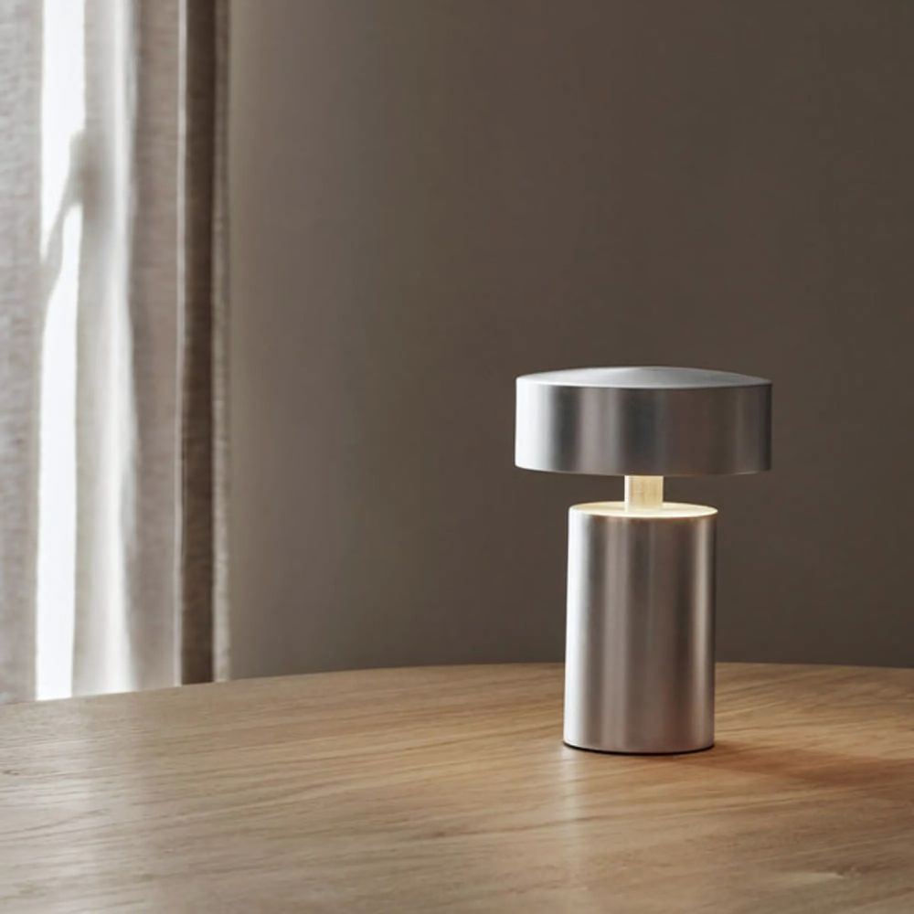 Silver column LED table lamp with a minimalist design, casting a warm ambient glow.