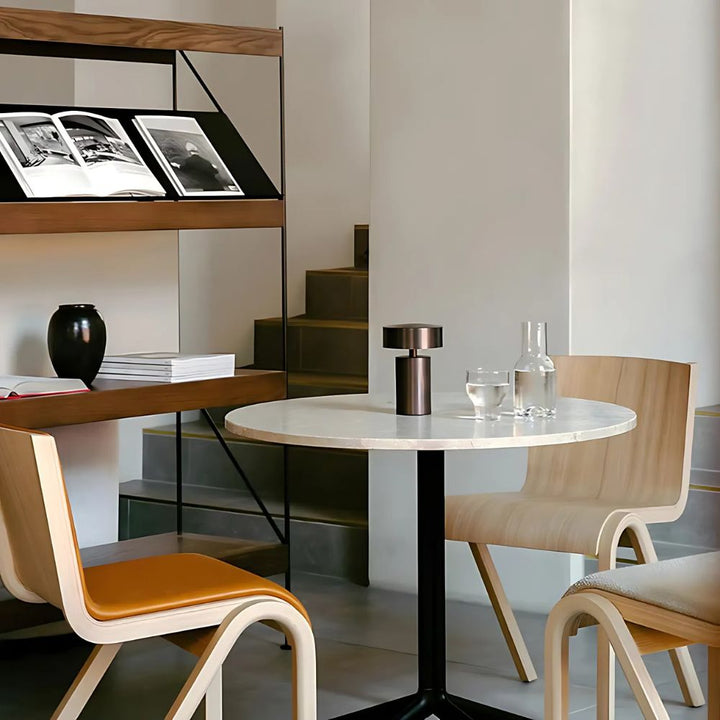 A modern, minimalist Column LED Table Lamp with a bronze finish sits on a round marble table.