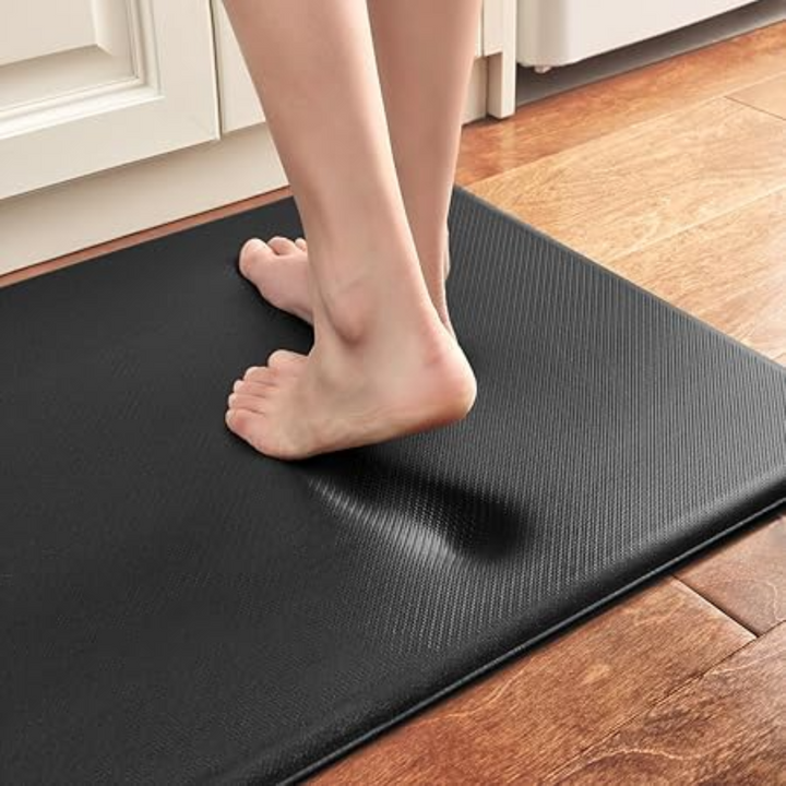 Black anti-fatigue kitchen mat with a textured surface, showing a person&