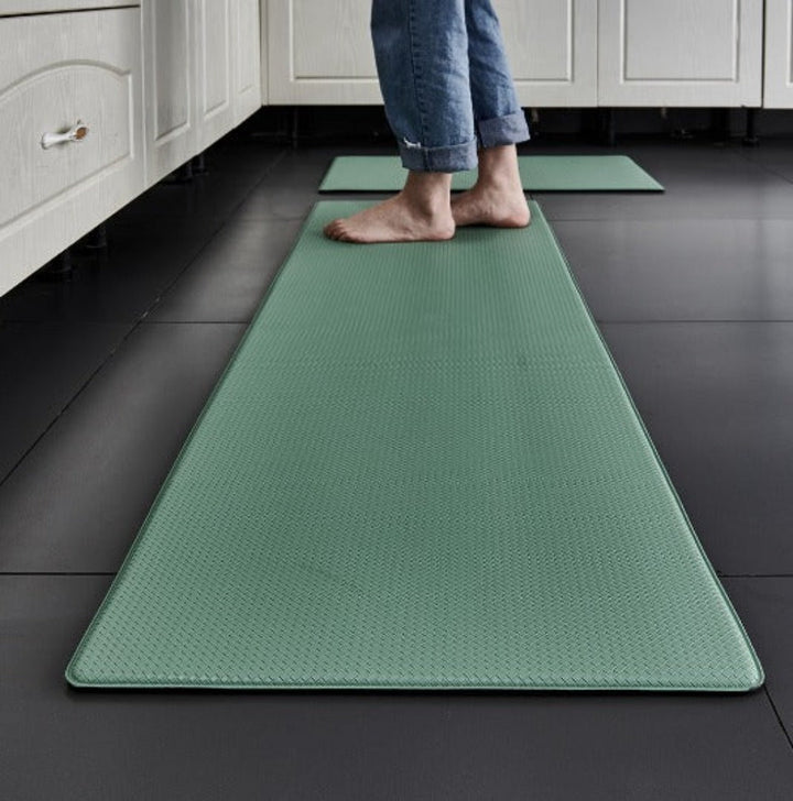 Green anti-fatigue kitchen mat with a textured surface on a dark floor.