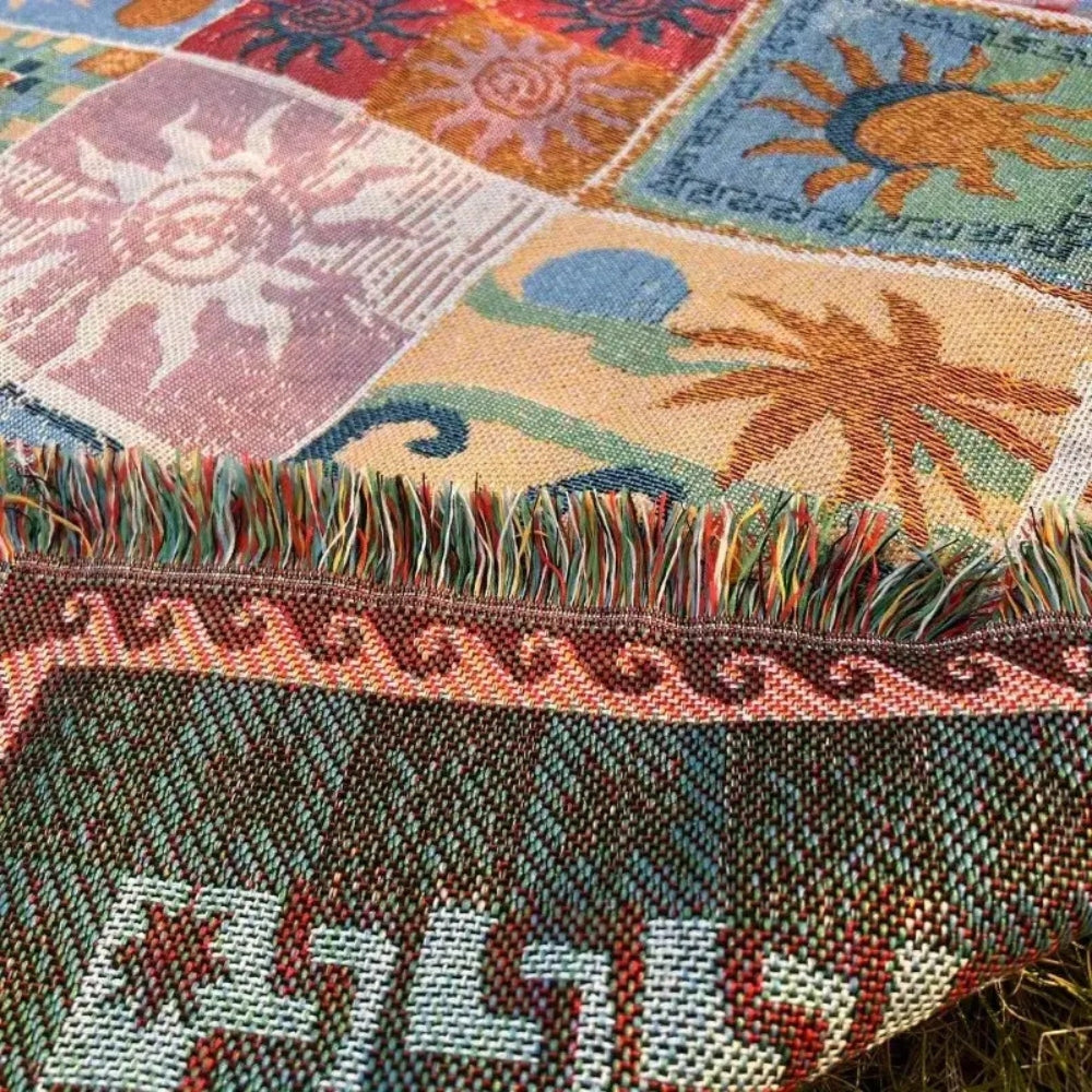Woven blanket with a patchwork of sun designs and a fringed edge.