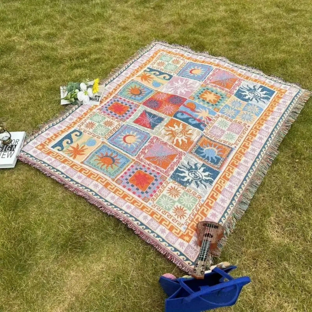 Colorful picnic blanket with sun and wave patterns spread on grass.