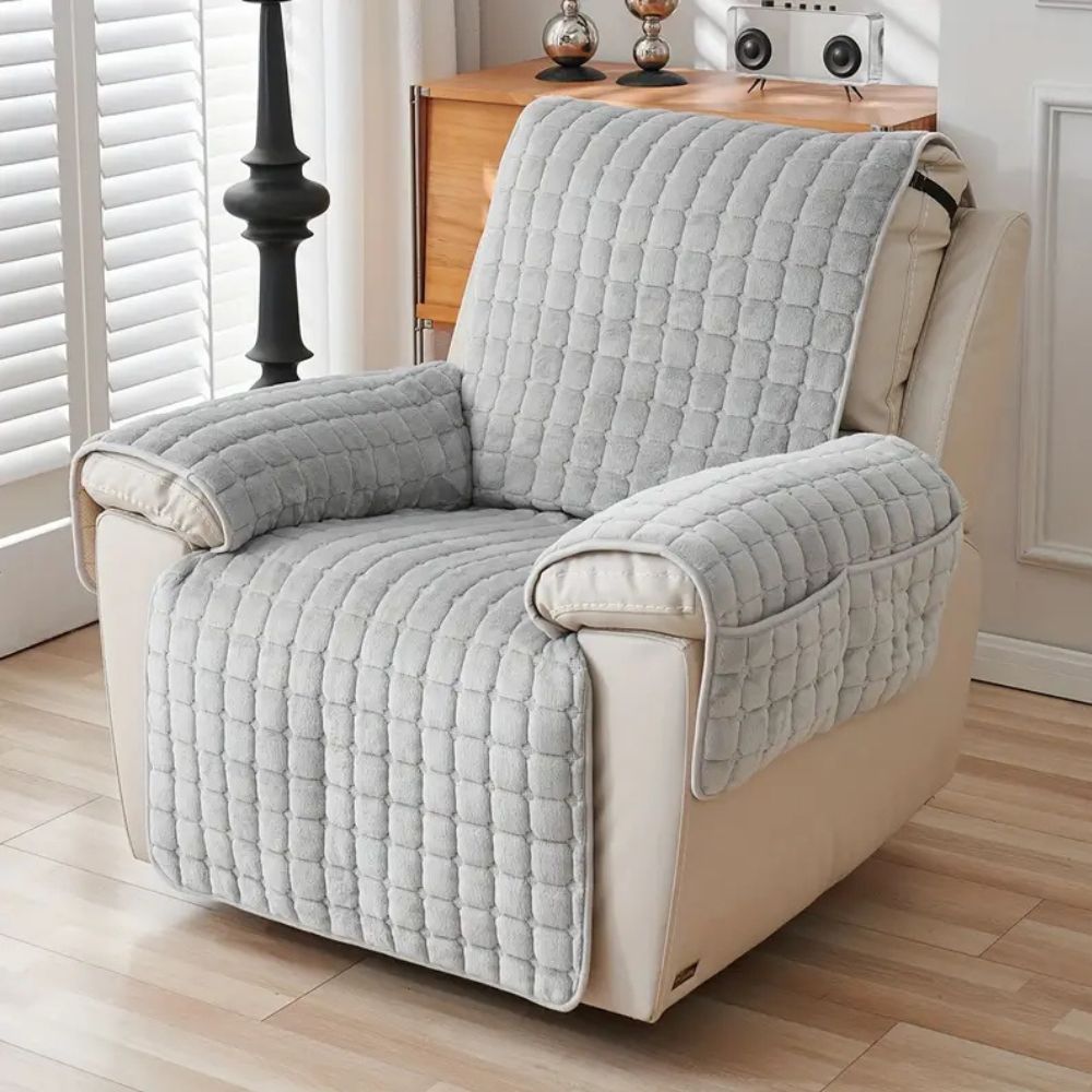 Gray quilted recliner chair cover with side pockets on a cream recliner.