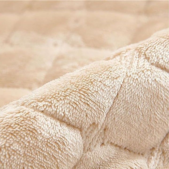 Close-up of a beige quilted recliner chair cover made of soft, plush fabric.
