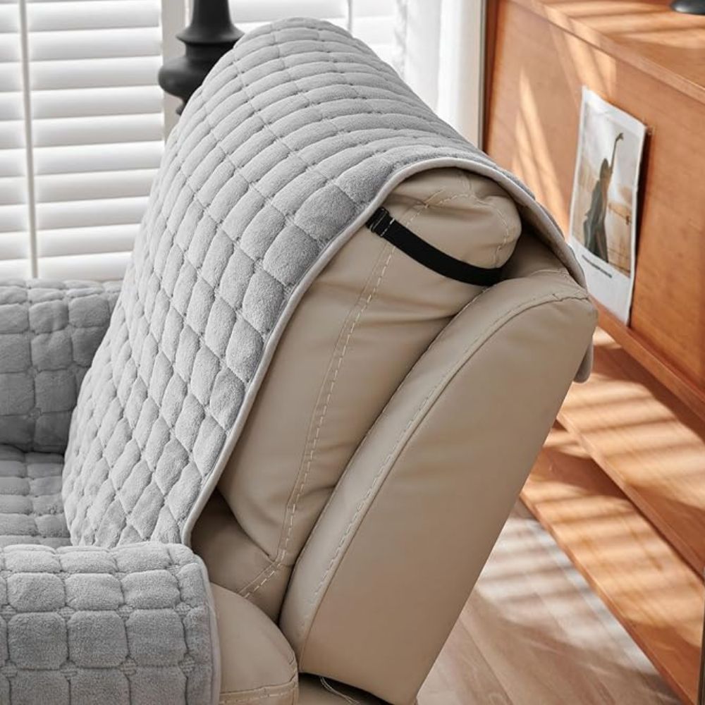 Light gray quilted recliner chair cover draped over a tan leather recliner armrest.