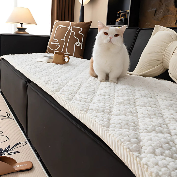 White quilted sofa cover with textured geometric pattern, protecting a black sofa.