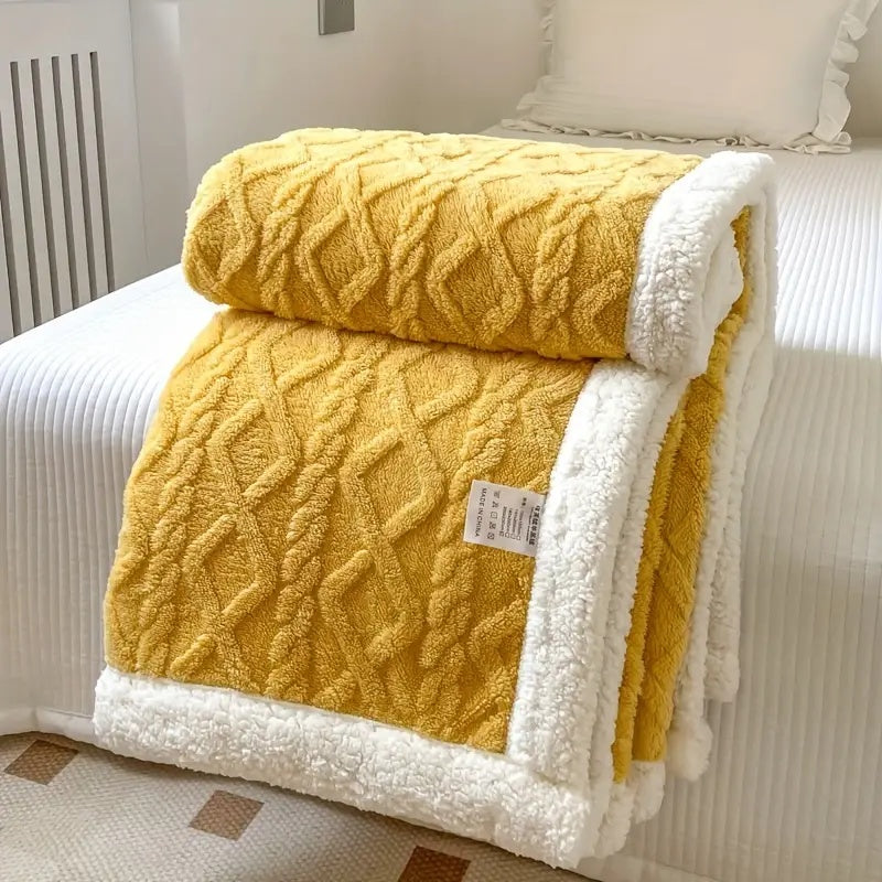 Yellow sherpa fleece throw blanket with white sherpa trim folded on a bed.