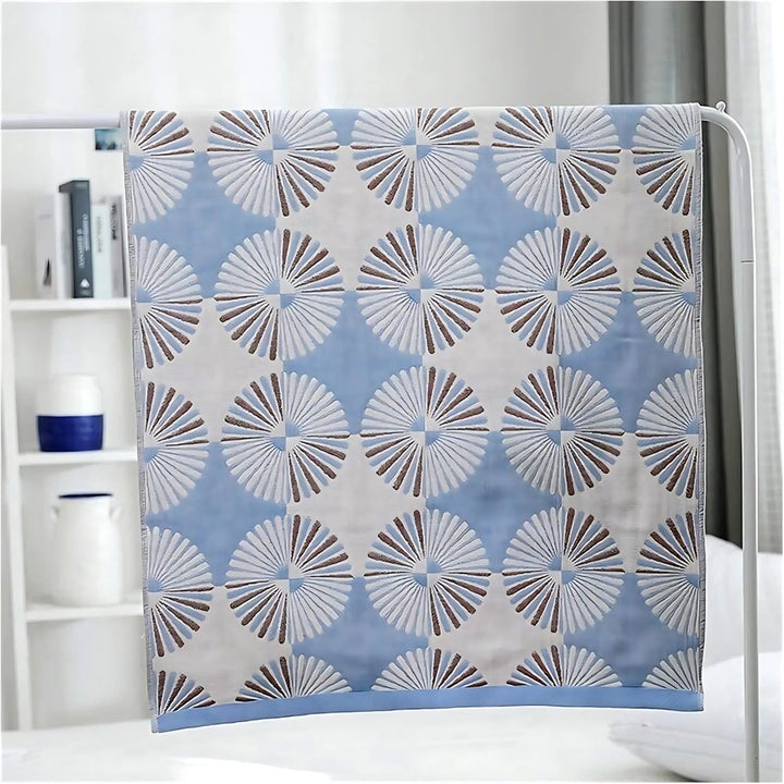 Blue cotton bath towel with a repeating pattern of white and brown dahlia-like floral designs.