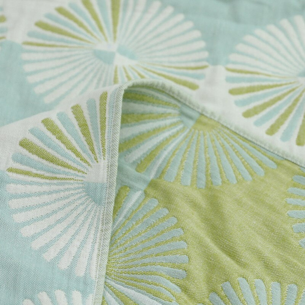 Close-up of a light blue and green Dahlia Blossom cotton bath towel with a woven jacquard floral pattern.
