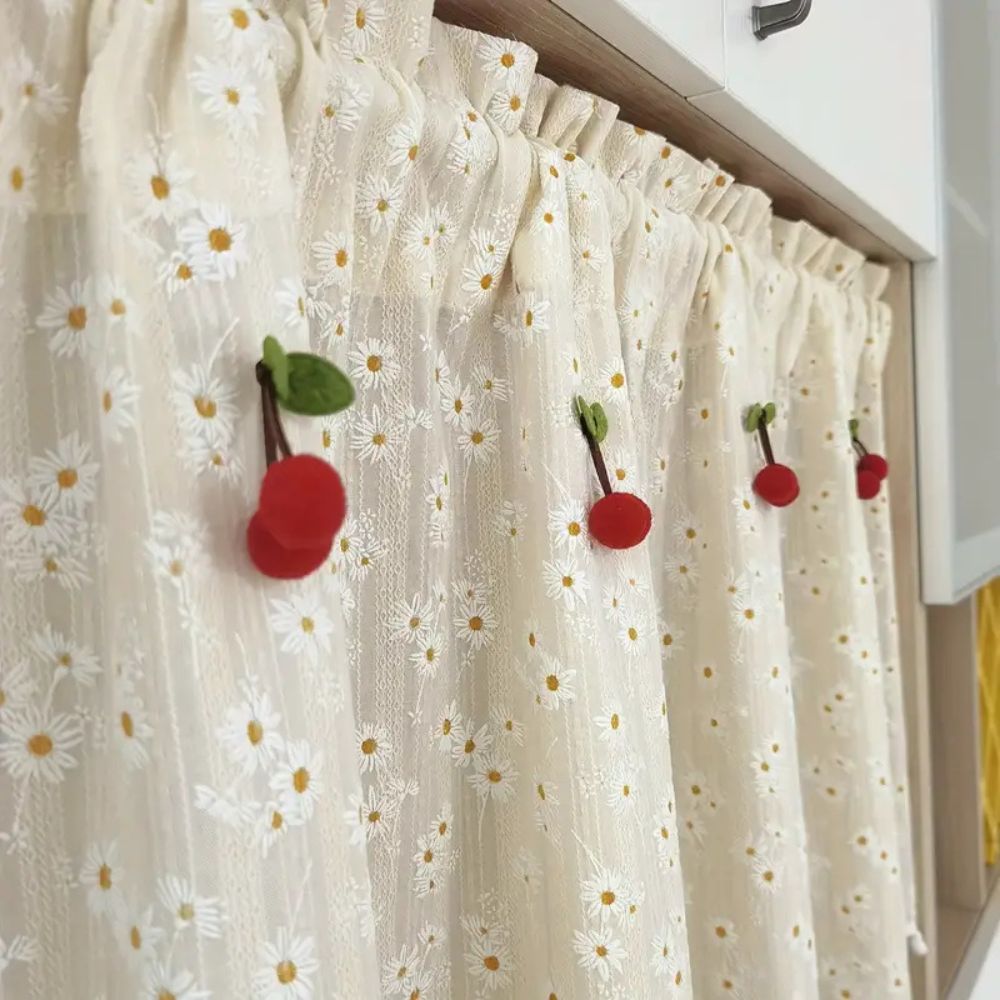 Cream cabinet curtain with a daisy pattern and decorative red cherries with green leaves.
