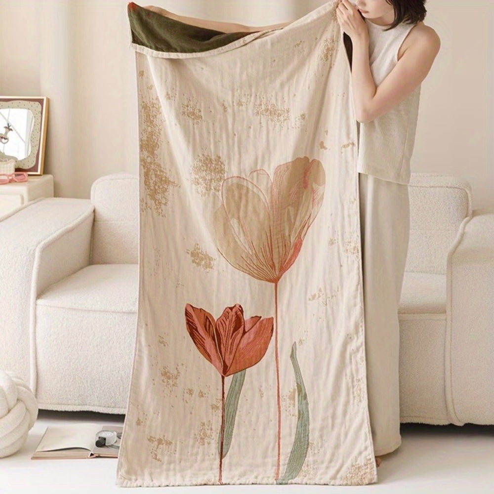 A woman holds a cream-colored cotton towel blanket with a vintage floral print of two tulips.
