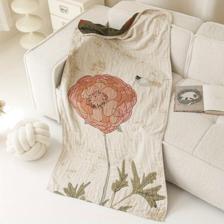 A cream-colored cotton towel blanket with a large pink and orange floral print draped over a white sofa.