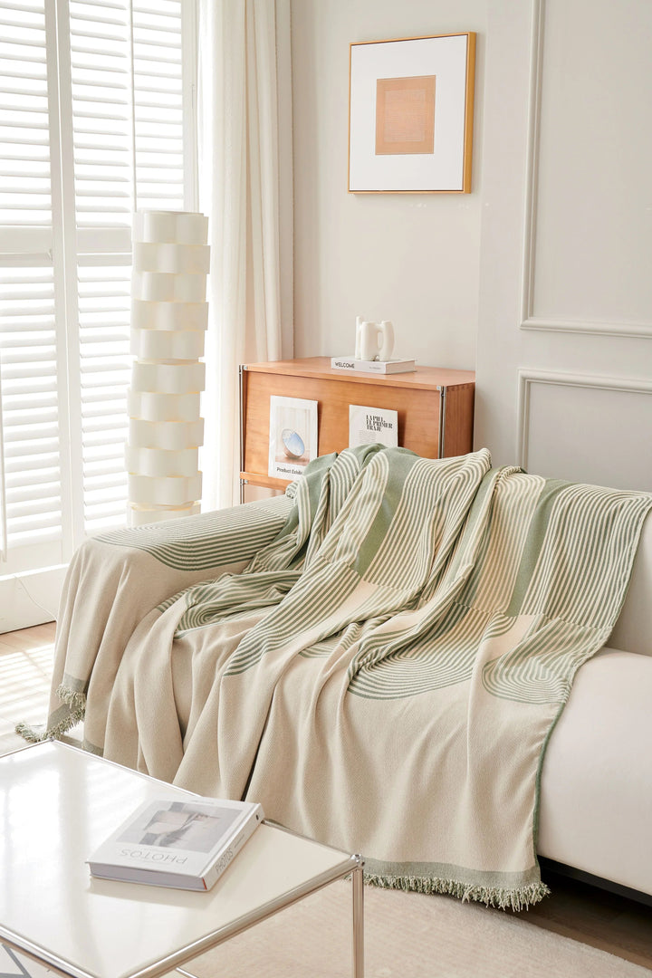 Pistachio green chenille throw blanket with white stripes draped over a white sofa.