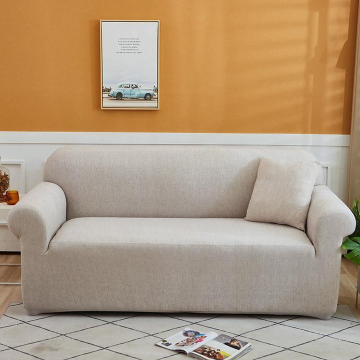 Egg shell colored couch cover with a cross pattern, featuring a pillow on the right side.