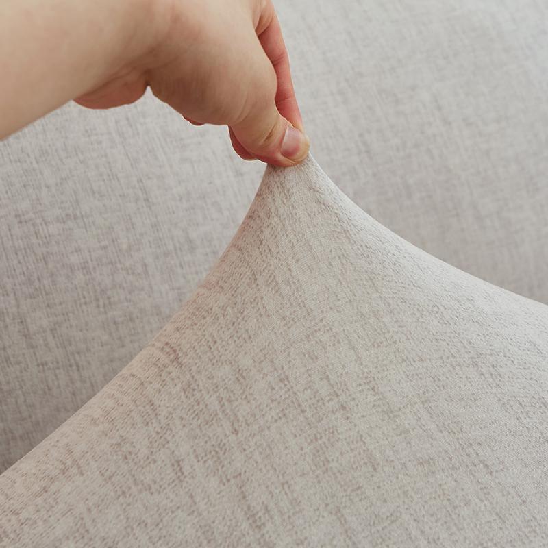 Hand stretching an eggshell colored couch cover with a subtle cross pattern.