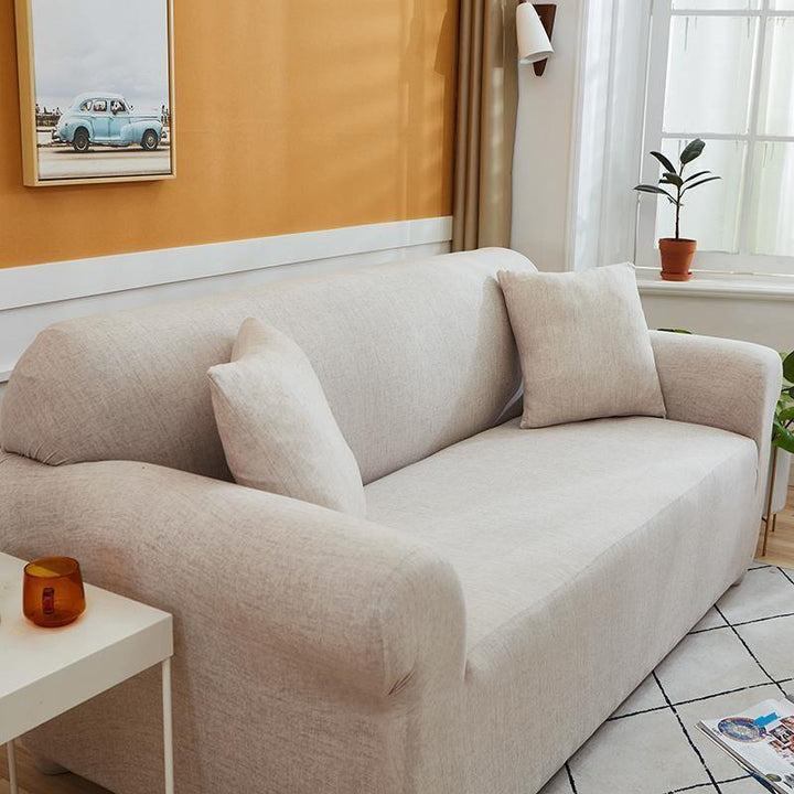 Egg shell colored couch cover with a cross pattern, featuring two throw pillows.