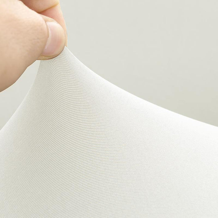 Close-up of a hand stretching a white, textured couch cover fabric.