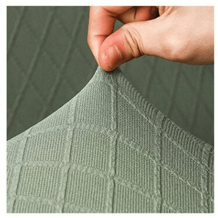 Hand stretching pale green wide jacquard couch cover made of soft micro-fabric.