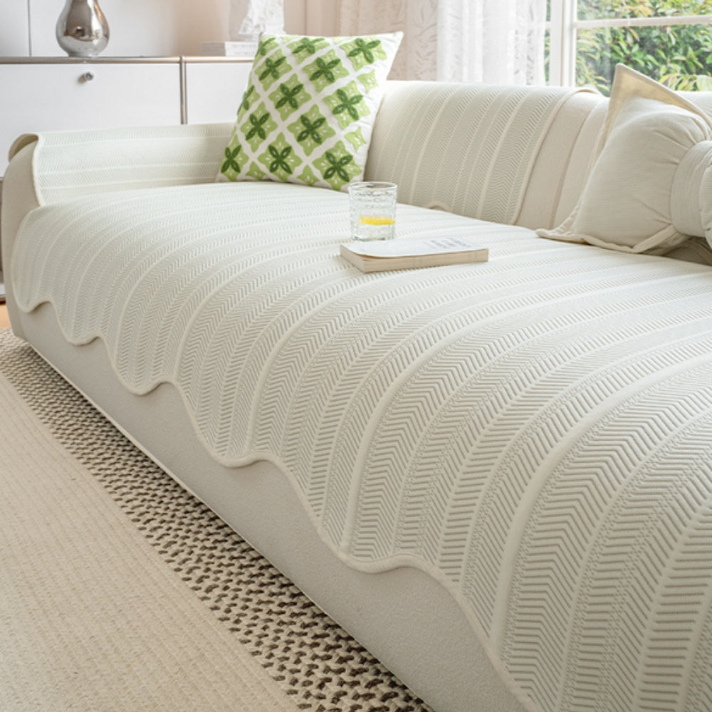 Cream herringbone sofa cover with a scalloped edge draped over a sofa.