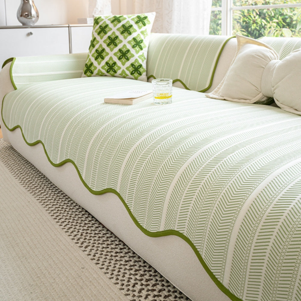 Herringbone sofa cover with green scalloped trim and a decorative pillow.