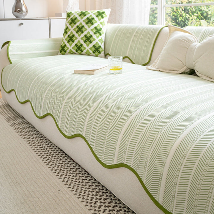 Herringbone sofa cover with green scalloped trim and a decorative pillow.