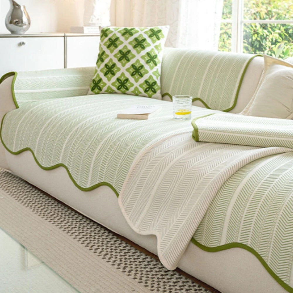 Light green herringbone sofa cover with scalloped edges and a decorative pillow.
