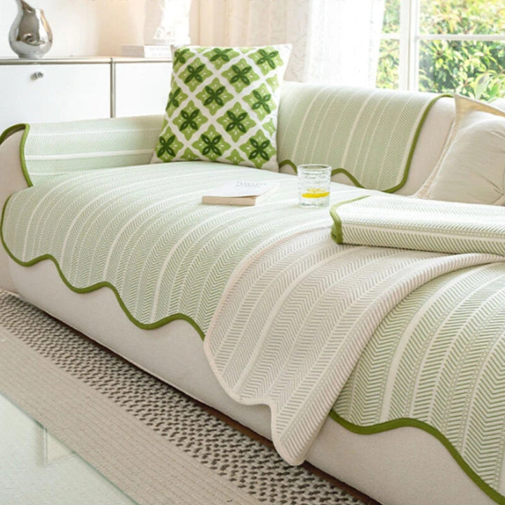 Light green herringbone sofa cover with scalloped edges and a decorative pillow.