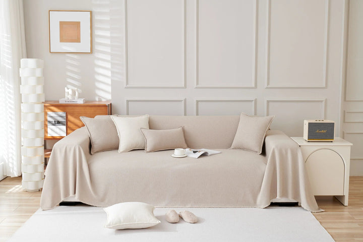 Milk Tea Soft Throw Blanket draped over a sofa with decorative pillows and a small speaker on a side table.