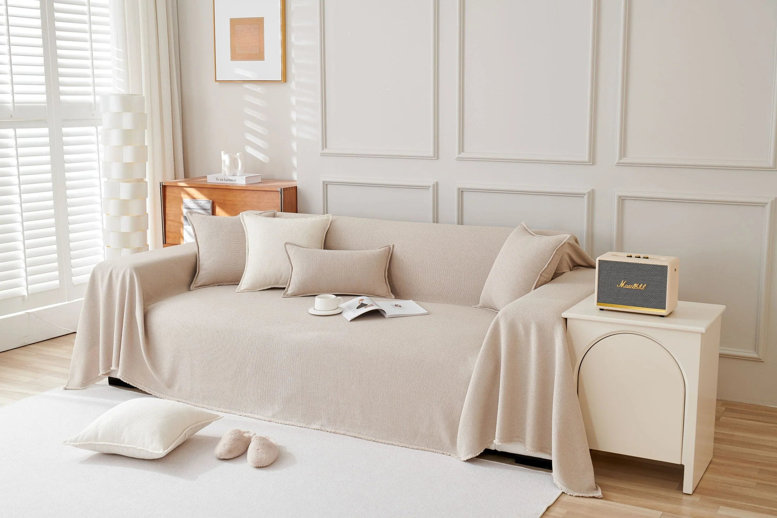 Milk Tea soft throw blanket draped over a sofa with decorative pillows and a Marshall speaker on a side table.