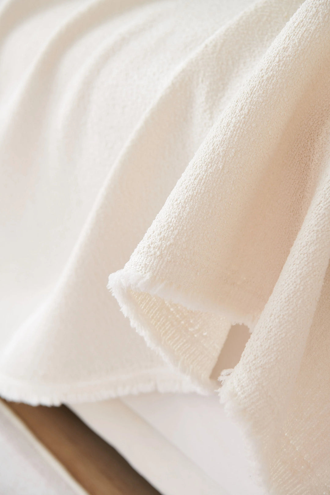 Off-white soft throw blanket with a textured weave and frayed edges.