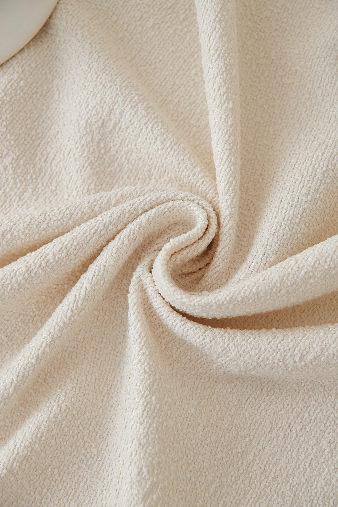 Off-white soft throw blanket with textured fabric, draped in a swirl.