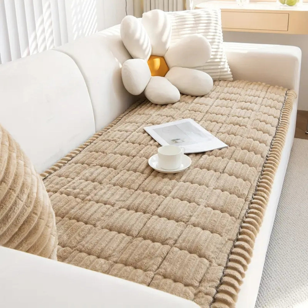 Plush microfiber sofa cover in tan with hand-pleated edges, featuring a white flower pillow and a teacup.