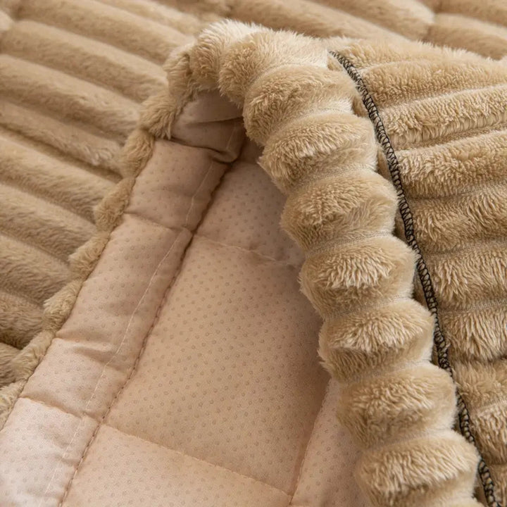 Close-up of a plush sofa cover with hand-pleated edges and a non-slip backing.