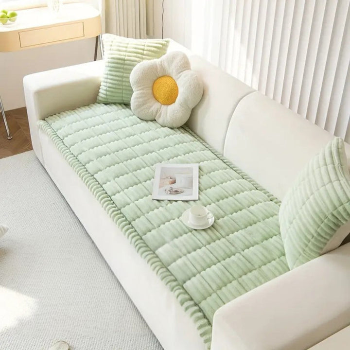 Light green plush microfiber sofa cover with hand-pleated edges and decorative pillows.
