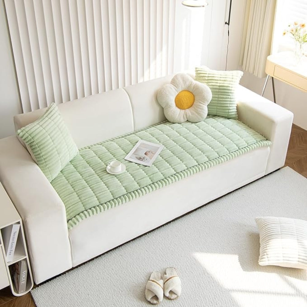 Plush microfiber sofa cover in light green with hand-pleated edges, featuring a flower-shaped pillow and a striped cushion.