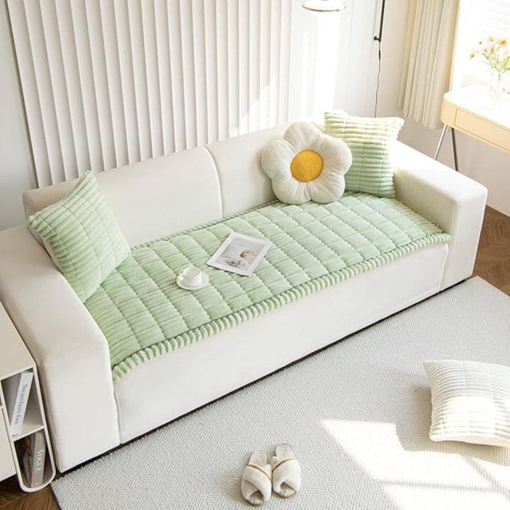 Plush microfiber sofa cover in light green with hand-pleated edges, featuring a flower-shaped pillow and a striped cushion.
