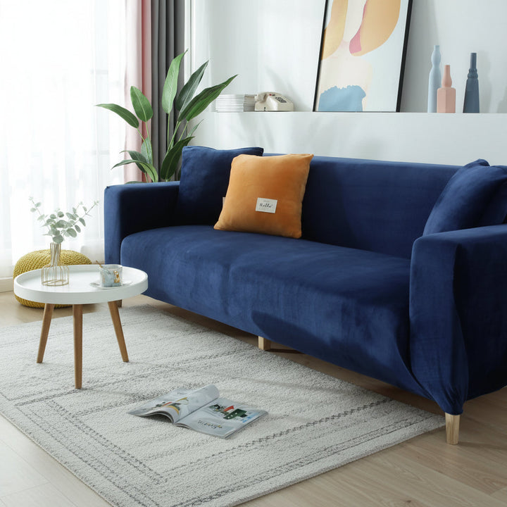 Navy blue velvet couch cover on a sofa with an orange accent pillow.