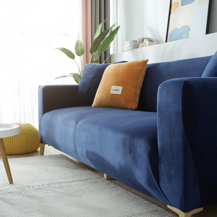 Navy blue velvet couch cover draped over a sofa with an orange accent pillow.