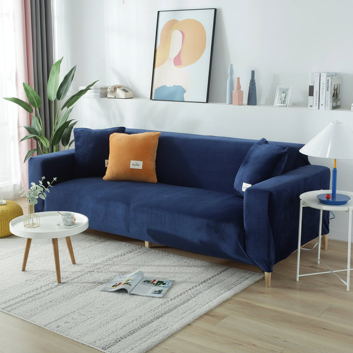 Navy blue velvet couch cover with orange and blue accent pillows on a sofa.