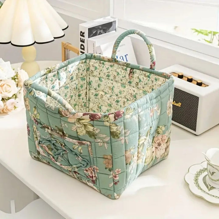 Floral canvas storage basket with handles and exterior pockets, featuring a light green background with a floral pattern.